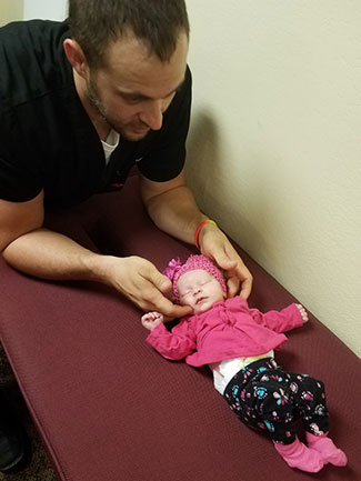 Dr. Kyle Ellensohn adjusting an infant