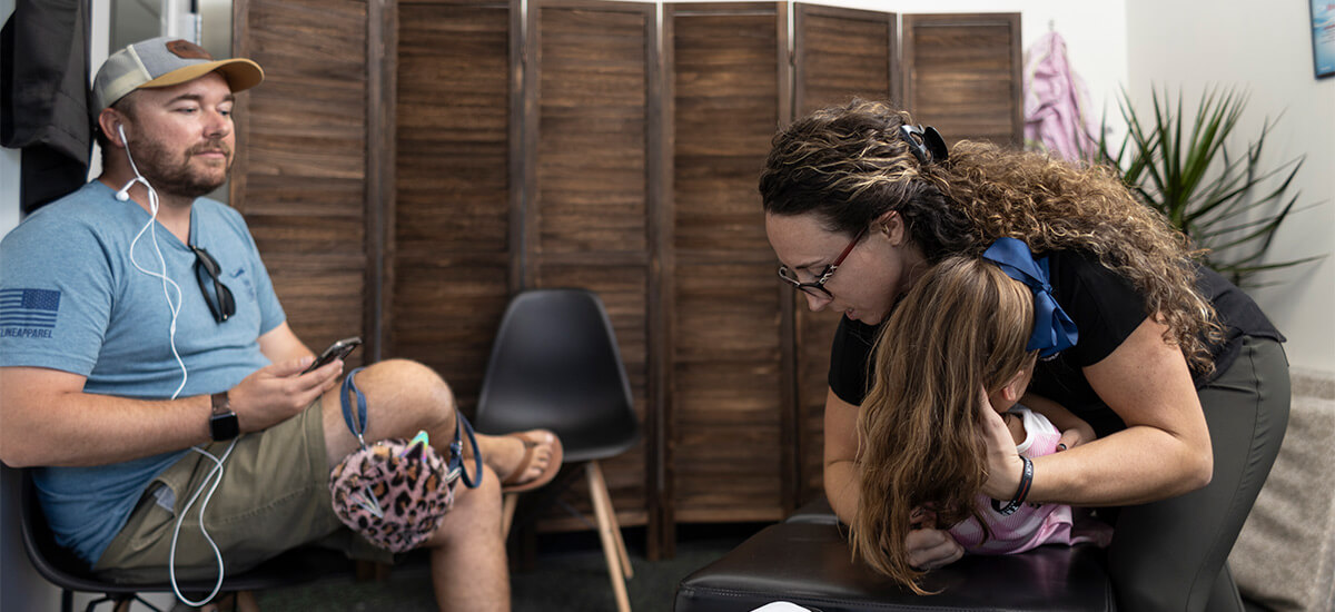 Trailhead Family Chiropractic's Dr Taylor adjusting patient with dad sitting nearby