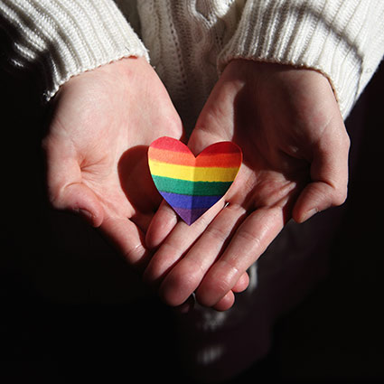 person holding rainbow heart shape in hand