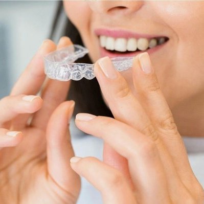 woman placing invisalign clear aligner into mouth