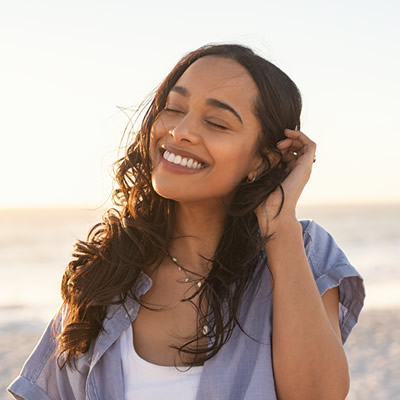 smiling woman brushing hair on the beach