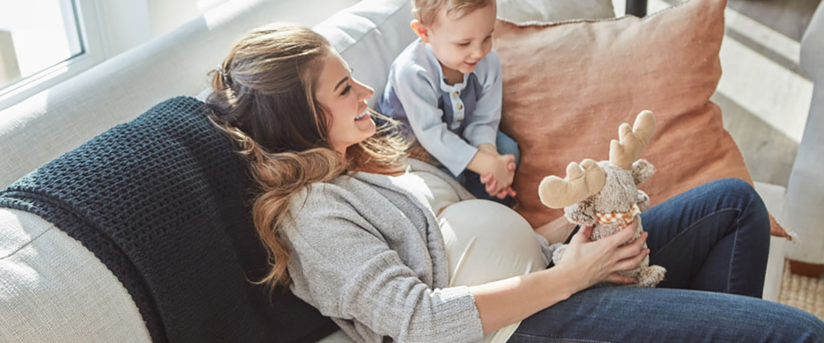 happy pregnant mom and kid on couch