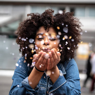 woman blowing confetti at the camera