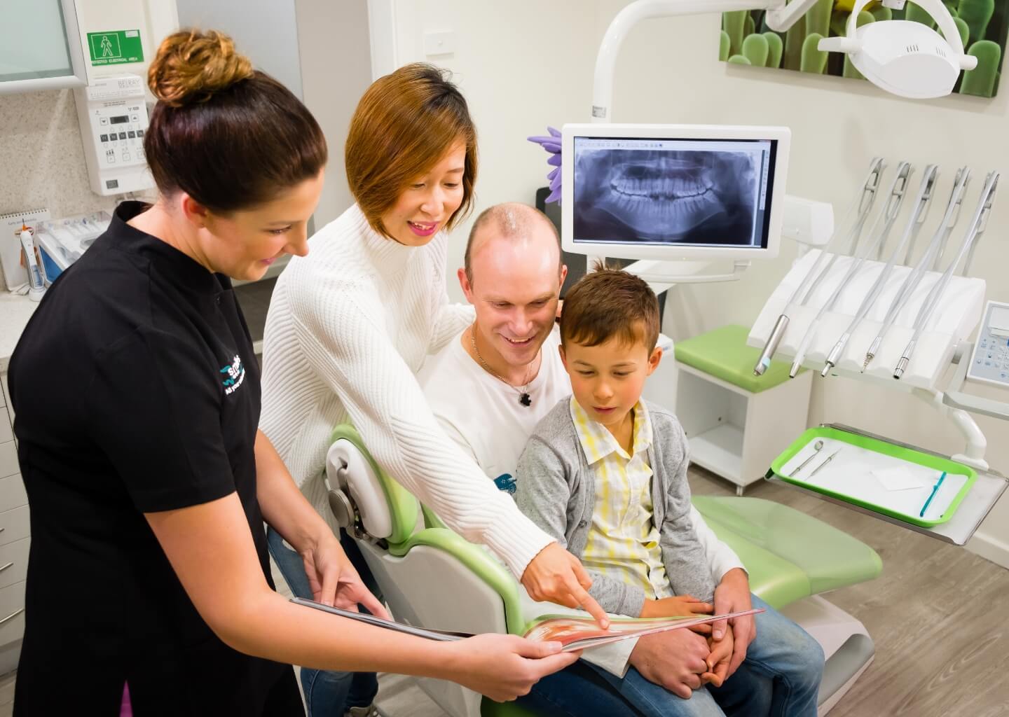 family in dental chair looking at xray