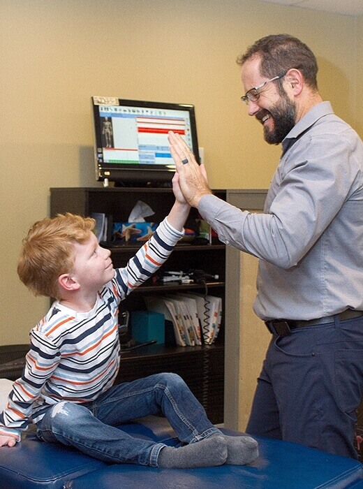 SE Calgary chiropractor Dr. Jeff high-fiving a boy