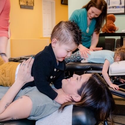 kid sitting on mom while at Lifetime Health & Wellness