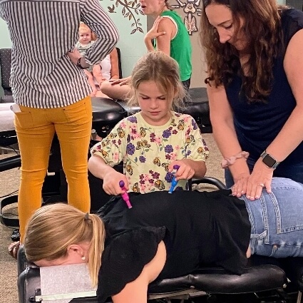 patient having back adjusted at Lifetime Health & Wellness while kid helps