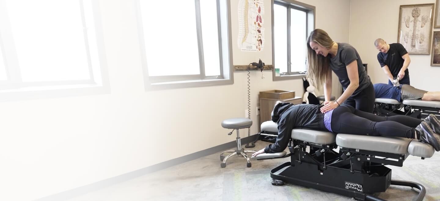 Chiropractors adjusting patients on two tables