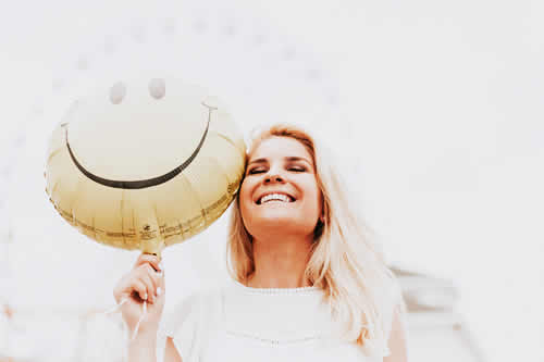 woman holding smiley balloon