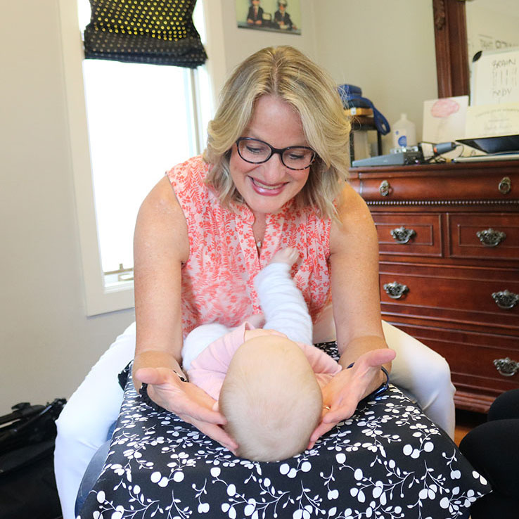 chiropractor leaning over baby smiling