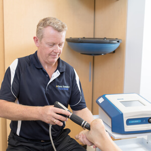 Gavin applying shockwave therapy to a patient's foot