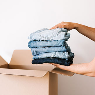 person putting clothes in a box to donate