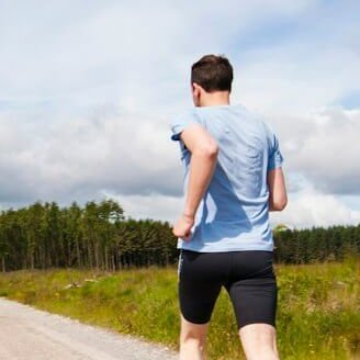 man running on road near grass field