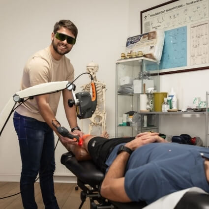 Dylan using shockwave therapy tool on patients knee