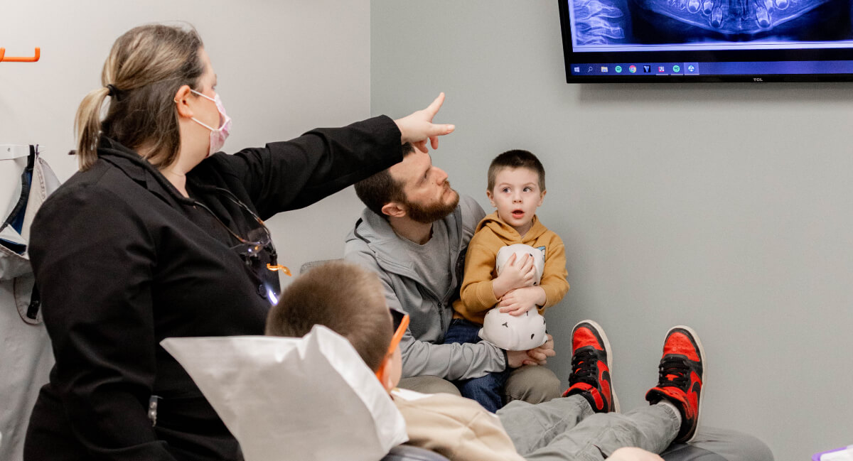 Dentist explaining x-ray to child and his father