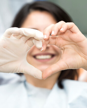 Patient and dentist making heart shape with their hands