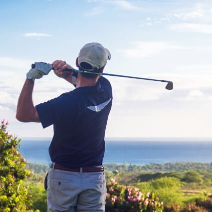 man swinging golf club on a sunny day