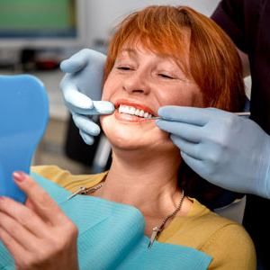 Woman in dentist chair admiring dental work in mirror