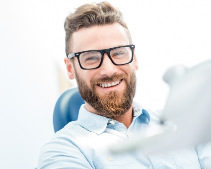 Man with glasses sitting on dental chair