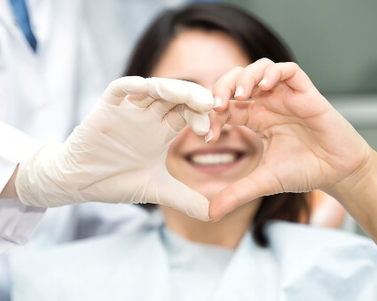 Patient and dentist making heart with hands