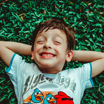 boy laying on grass smiling