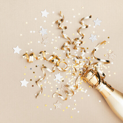 Gold champagne bottle with gold and silver ribbons coming out of bottle