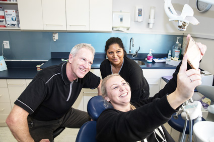 Dr Raymond taking selfie with patient and hygienist