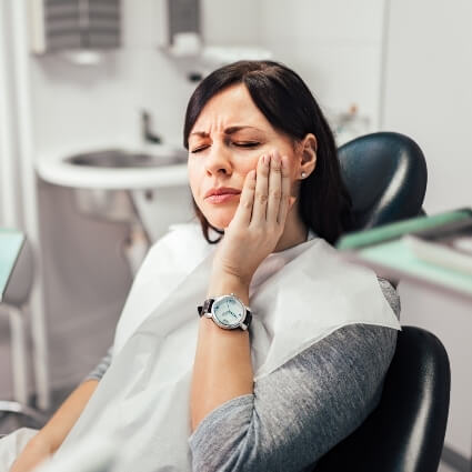 Female patient with jaw pain sitting on dental chair