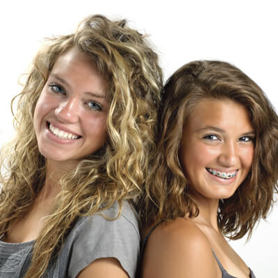 Two young smiling girls, one wearing braces