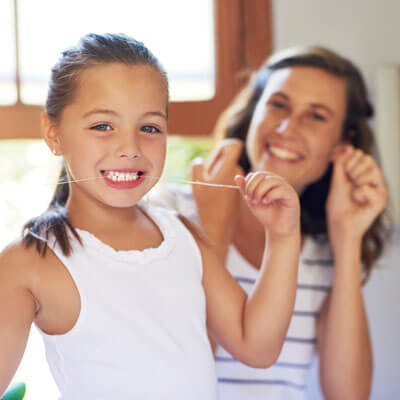 mom and daughter flossing teeth