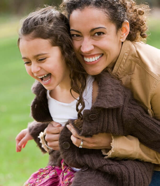 Mother and daughter laughing together at a park