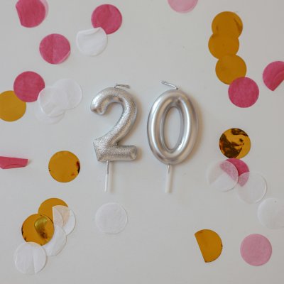 Silver number 20 candles surrounded by vibrant confetti on a light background. Perfect for celebrations.
