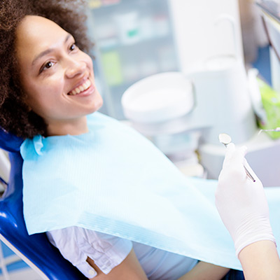 woman smiling while sitting in a dental chair