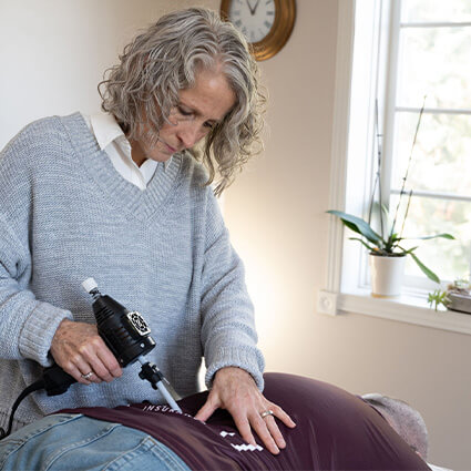 Dr Lisa adjusting patients back with a tool