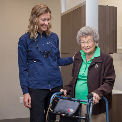 Dr. Oleson helping an older woman patient walk