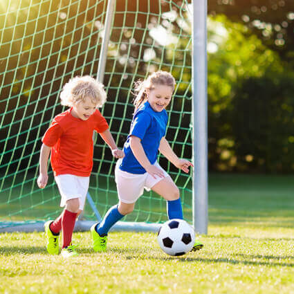 boy-and-girl-dribbling-soccer-ball-together-sq