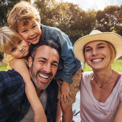 mother and father taking selfie with their two children while smiling