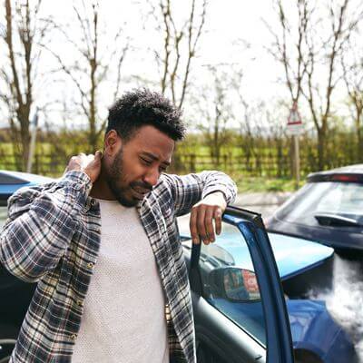 Man getting out of a car and holding his neck after car accident