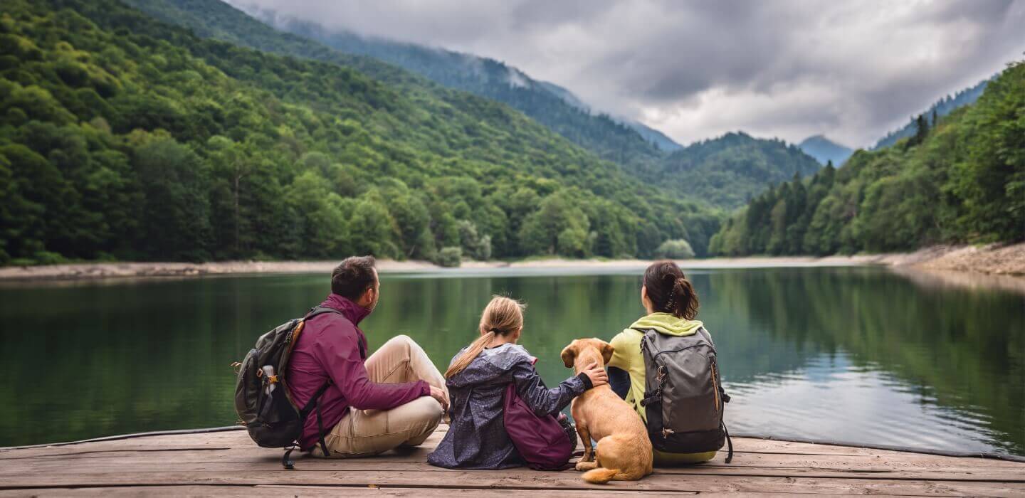 family sitting near lake outdoors