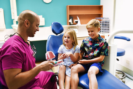 Dr Zaid Wall demonstrating brushing with two young children