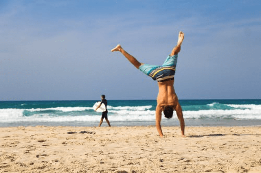 man on beach doing cartwheel