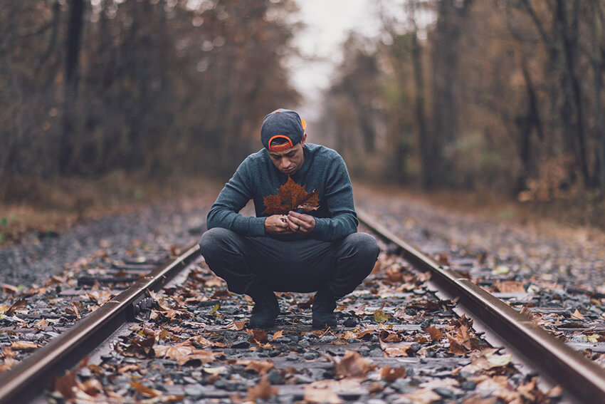 Man kneeling on train track