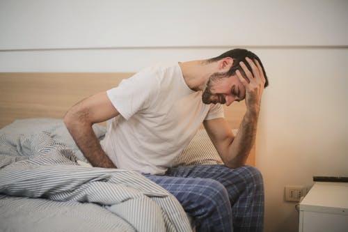 Man in bed holding head