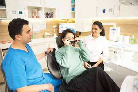 Patient putting on sunglasses sitting in dentist chair