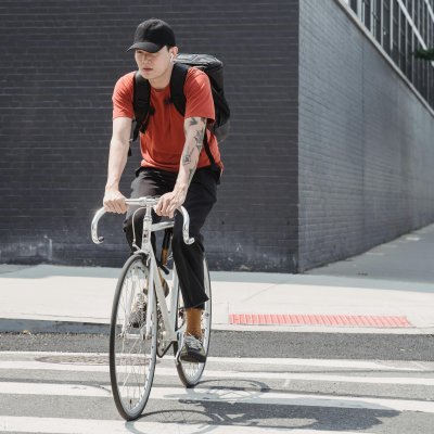 Man cycling on a city street zebra crossing with a modern backdrop.