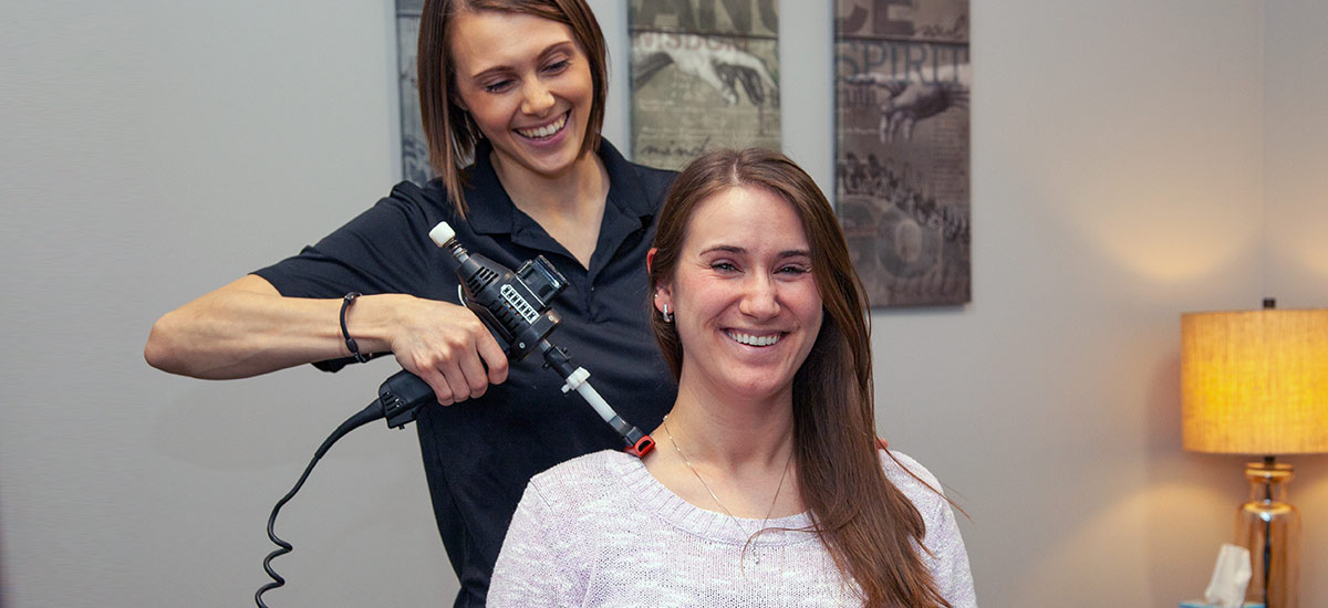 chiropractor adjusting a patient with a handheld tool