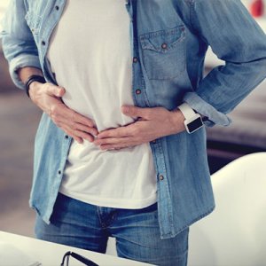 man with denim with hands on stomach
