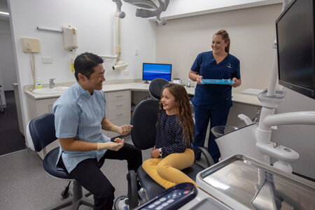 Dr Choi chatting with young girl sitting in dentist chair