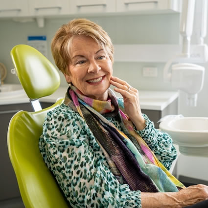 mature woman sitting during dental visit smiling
