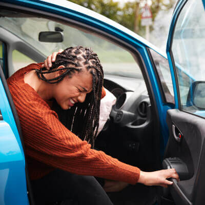 Woman exiting car in pain